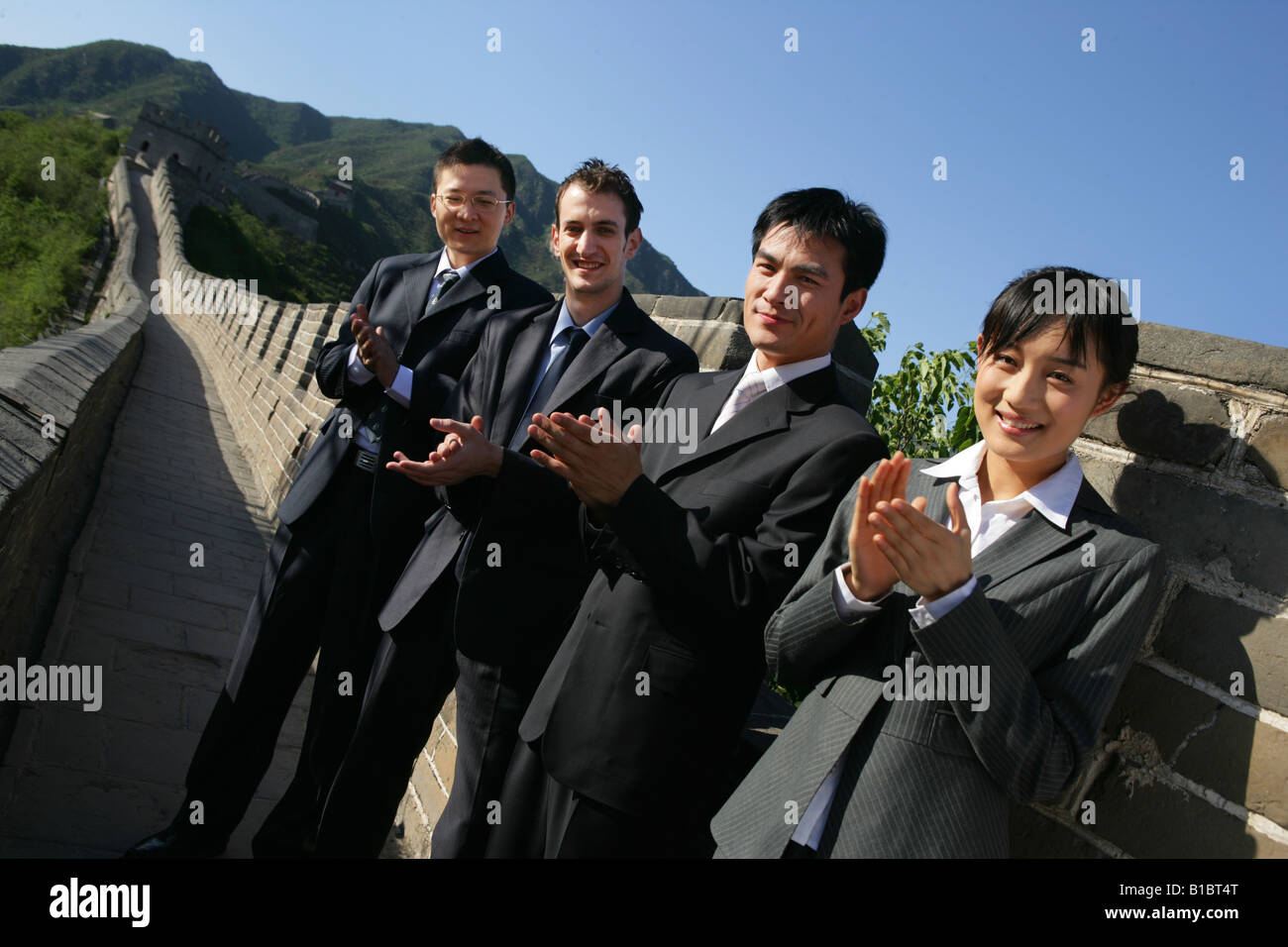 Tre uomini d affari e una imprenditrice battendo le mani sulla Grande Muraglia,Beijing, Cina Foto Stock