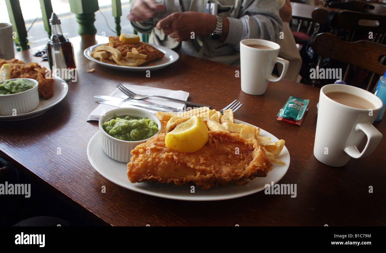 Fish n Chips e cedevole di piselli e una tazza di tè Foto Stock