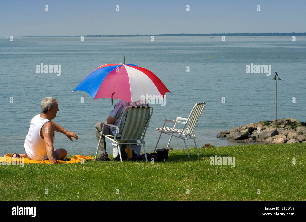 Due persone seduto su un orlo di erba che si affaccia il Solent prese a Lee on Solent il Beach Estate 2008 Foto Stock