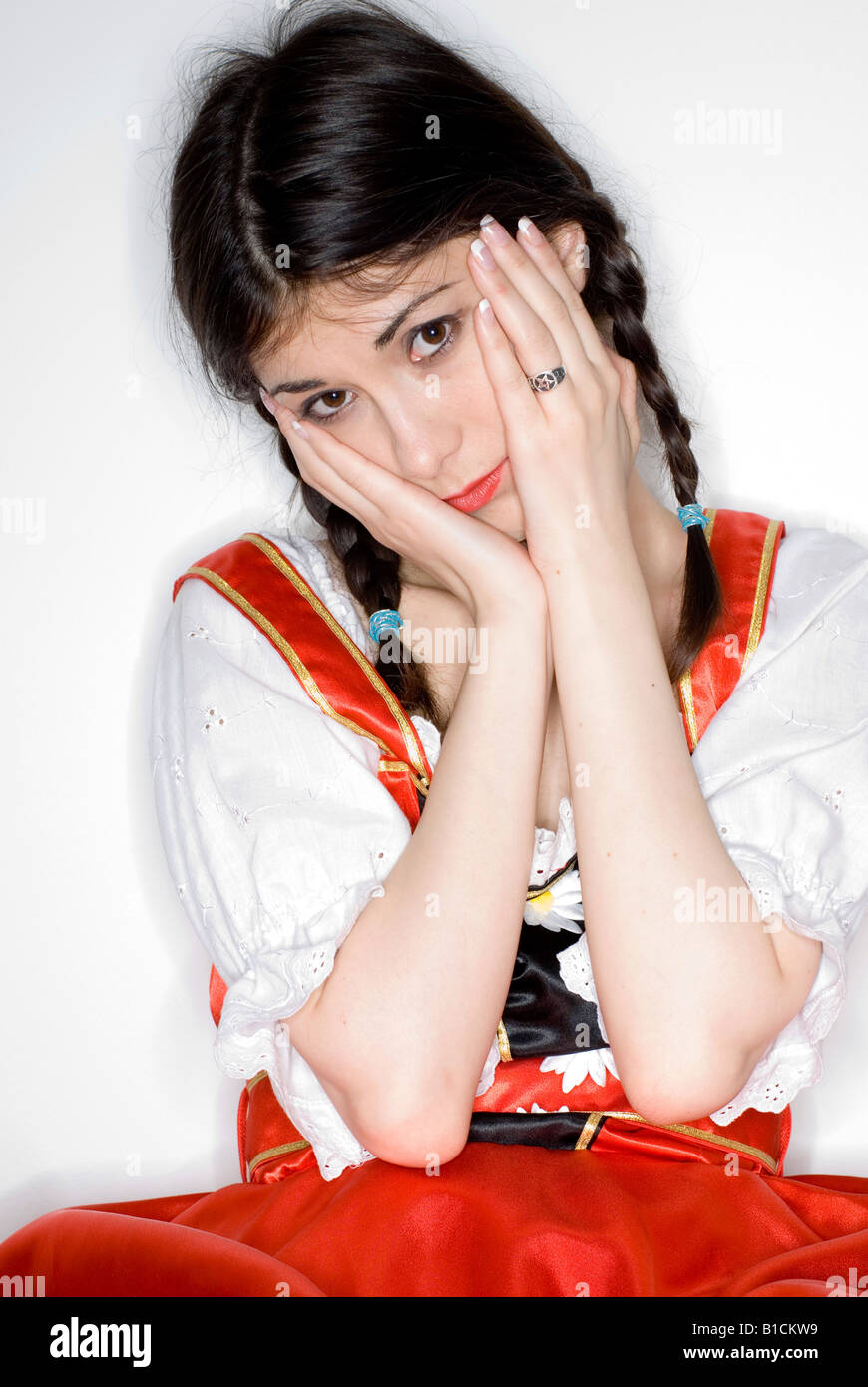 Giovane donna con due trecce che indossa un vestito con grembiule, interrogando guardare Foto Stock