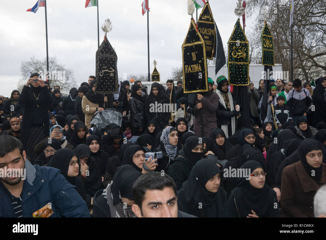 Una folla di musulmani sciiti con striscioni guarda la rievocazione del cammino di donne e bambini dopo il massacro di Karbala Foto Stock