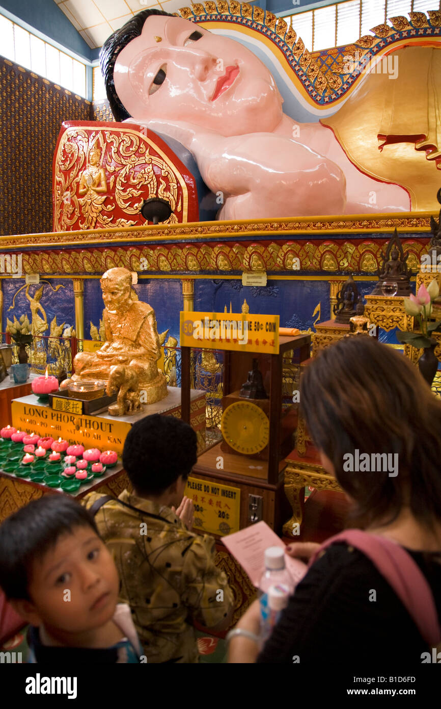 Donna malese, i bambini e la ruota della fortuna Wat Chayamangkalaram Buddha reclinato tempio, Lorong Birmania, Georgetown Penang Malaysia Foto Stock