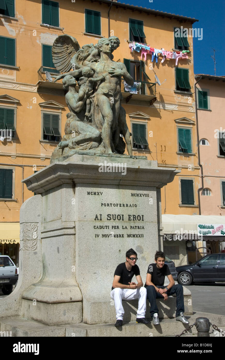 Ragazzi italiani di sedersi su un monumento ai caduti gli eroi di guerra in Portoferraio, Isola d'Elba (Isola d'Elba) Toscana Italia Foto Stock