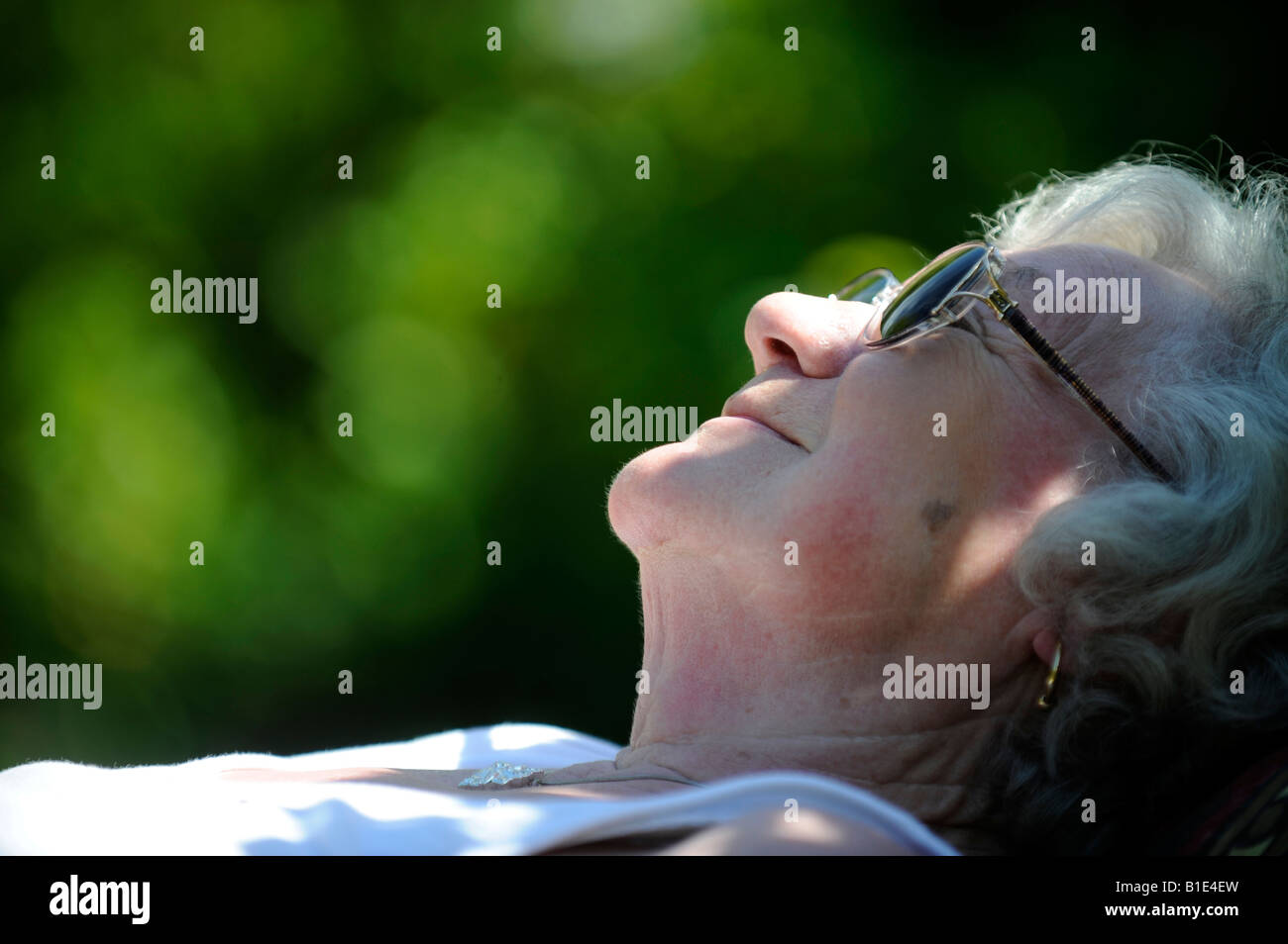 Una signora inglese titolare di pensione o di rendita OAP gode di pensionamento in una giornata di sole a prendere il sole,UK,Inghilterra. Foto Stock