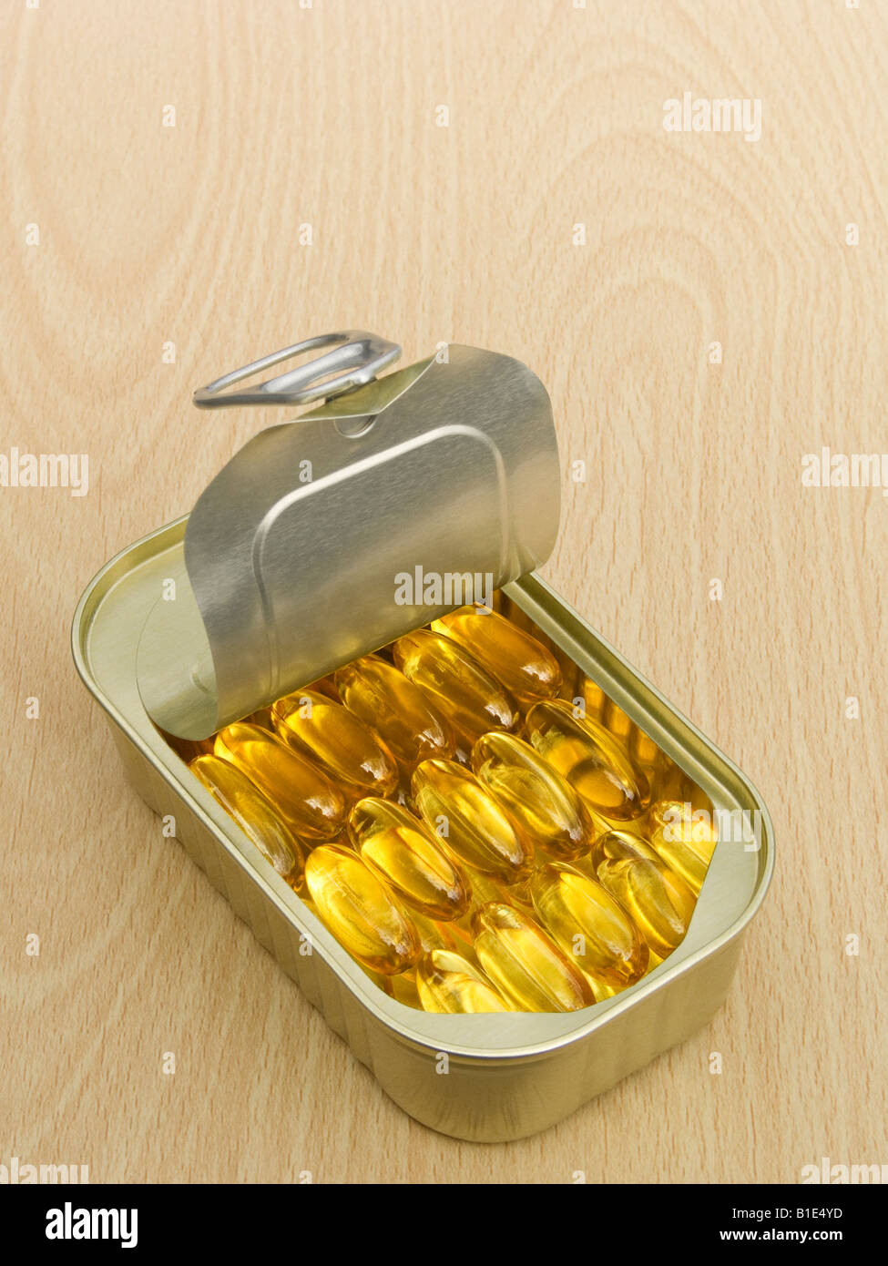 Olio di pesce capsule ordinatamente disposte in un anello di trazione dello stagno su una tavola di legno di superficie Foto Stock