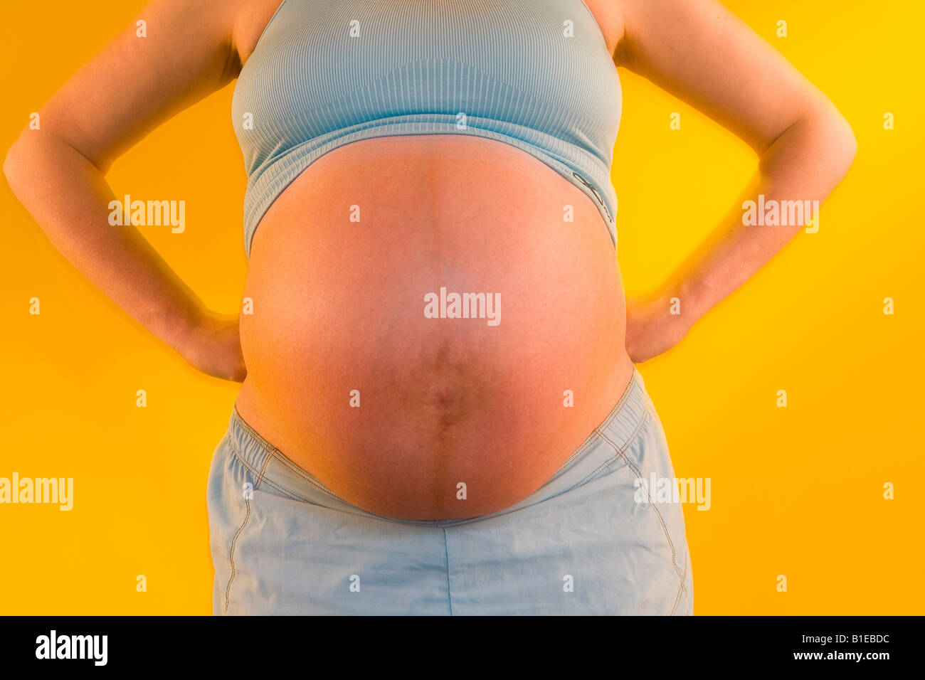 Vista frontale della donna incinta lo stomaco mentre indossa halter top e shorts Alaska Stati Uniti Foto Stock