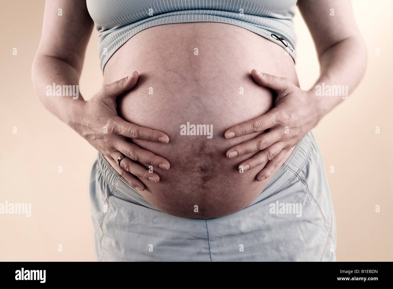 Vista frontale della donna incinta lo stomaco mentre indossa halter top e shorts Alaska Stati Uniti Foto Stock