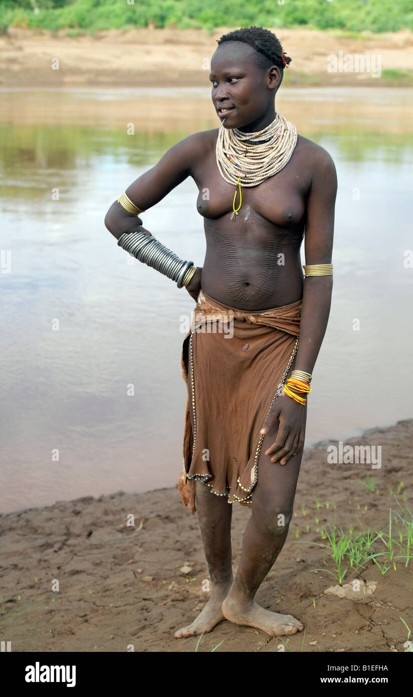 Un Karo ragazza sorge sulle rive del fiume Omo. È tradizione per le ragazze e le giovani donne per perforare un foro al di sotto del labbro inferiore Foto Stock
