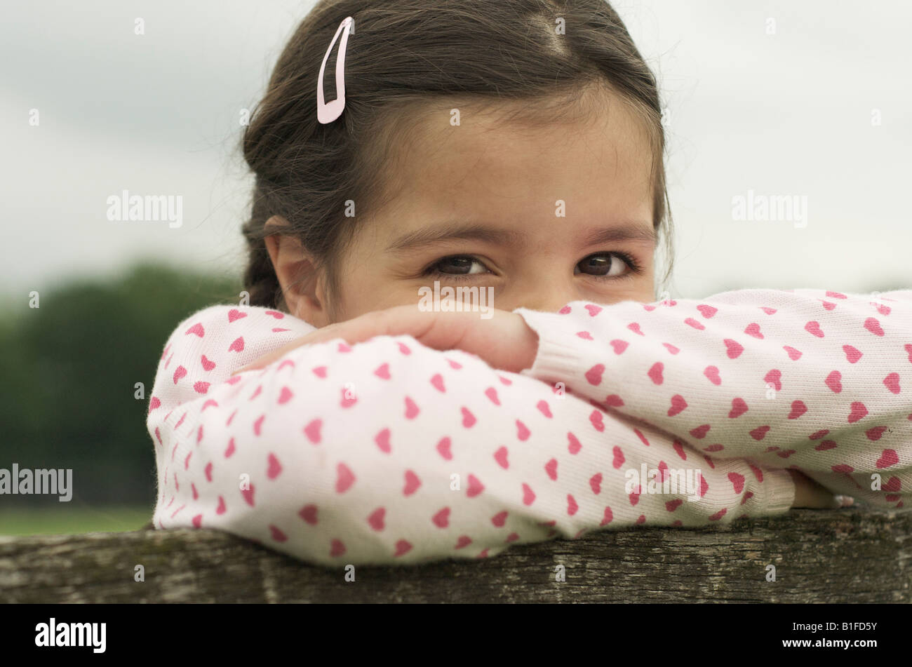 Close-up di un cild-6 anni, poggiando su una recinzione Foto Stock