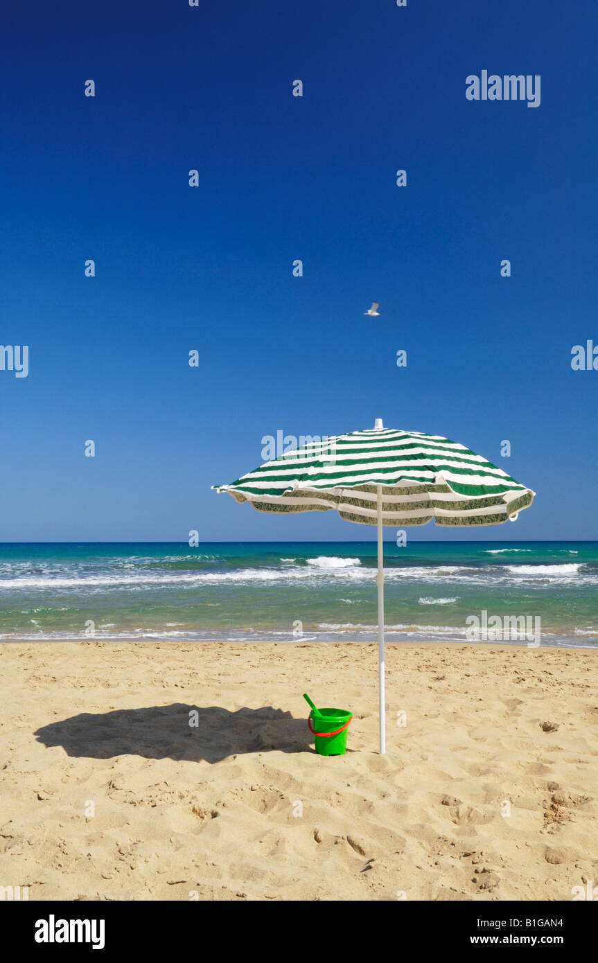 Un ombrellone stripo su una spiaggia di sabbia sul mare in estate. La Mata, Torrevieja, Spagna. Foto Stock