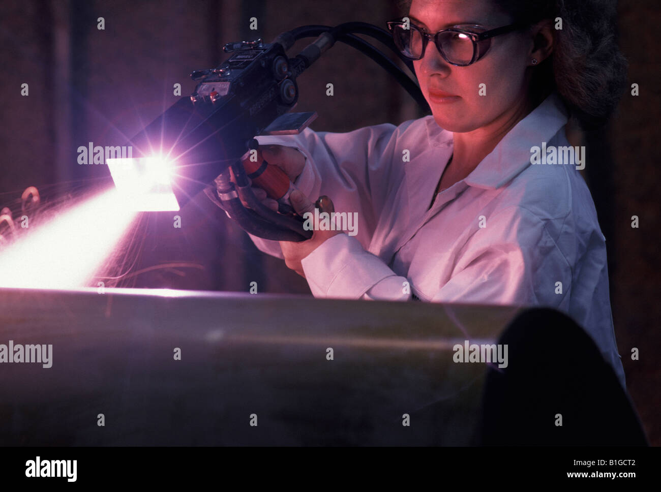 Un lavoratore di sesso femminile che di attacco in acciaio lavorato con un agente di corrosione al plasma Foto Stock