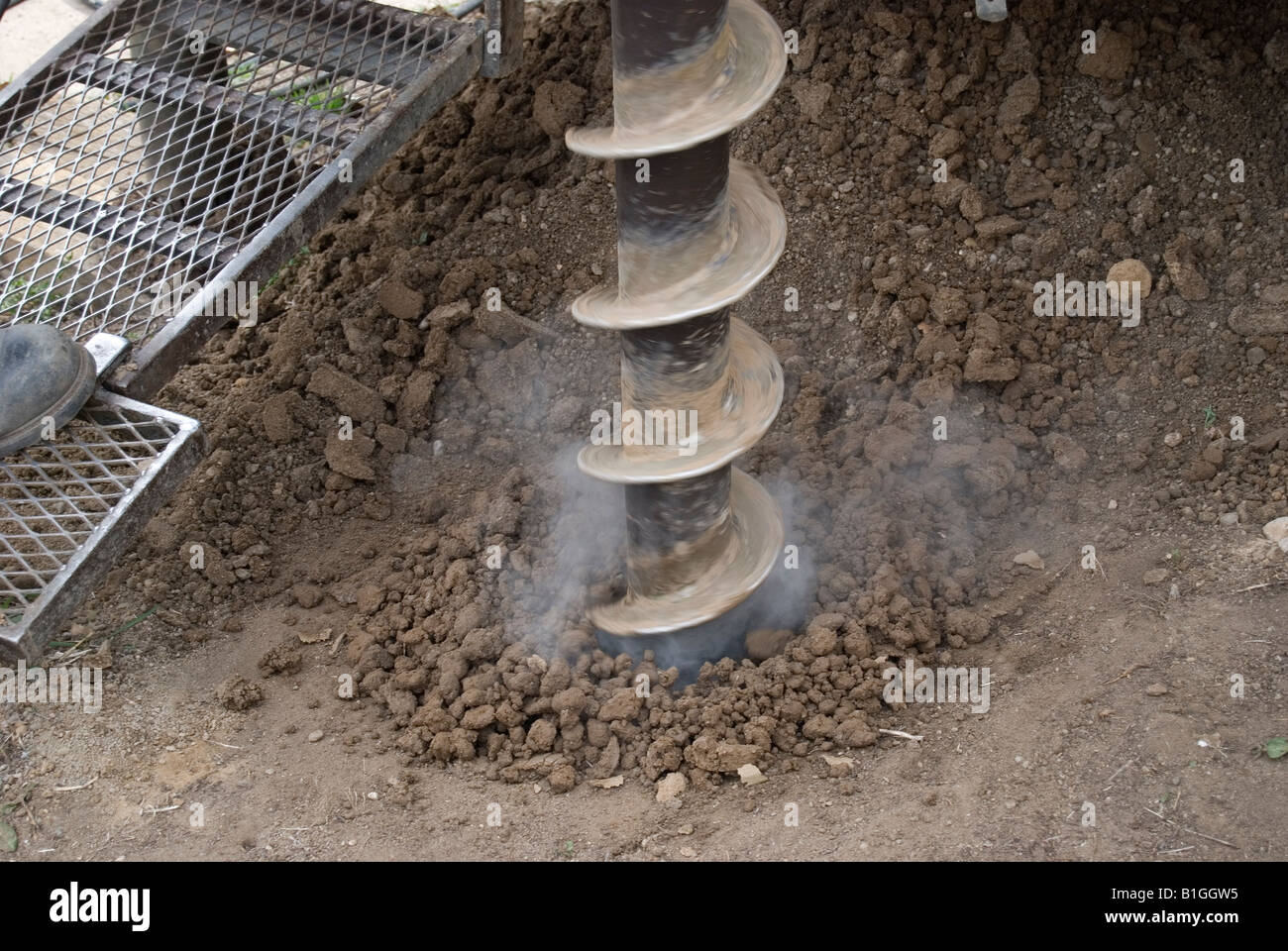 Aumento di vapore dai suoli e sfocata la filatura stelo cavo di perforazione della coclea noioso per raccogliere i campioni di suolo per l'analisi di laboratorio. Foto Stock