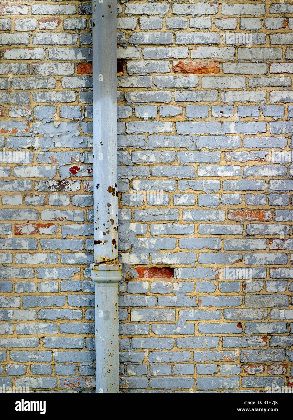 Vecchio muro in mattoni con il tubo ed il distacco della vernice Foto Stock