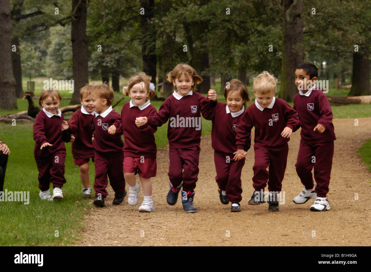 La scuola dei bambini in esecuzione attraverso un parco Foto Stock