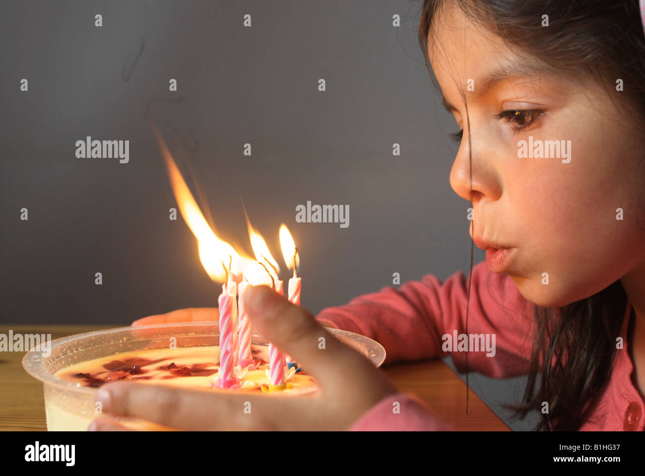 Sei anni ragazza soffia candele sulla torta di compleanno Foto Stock