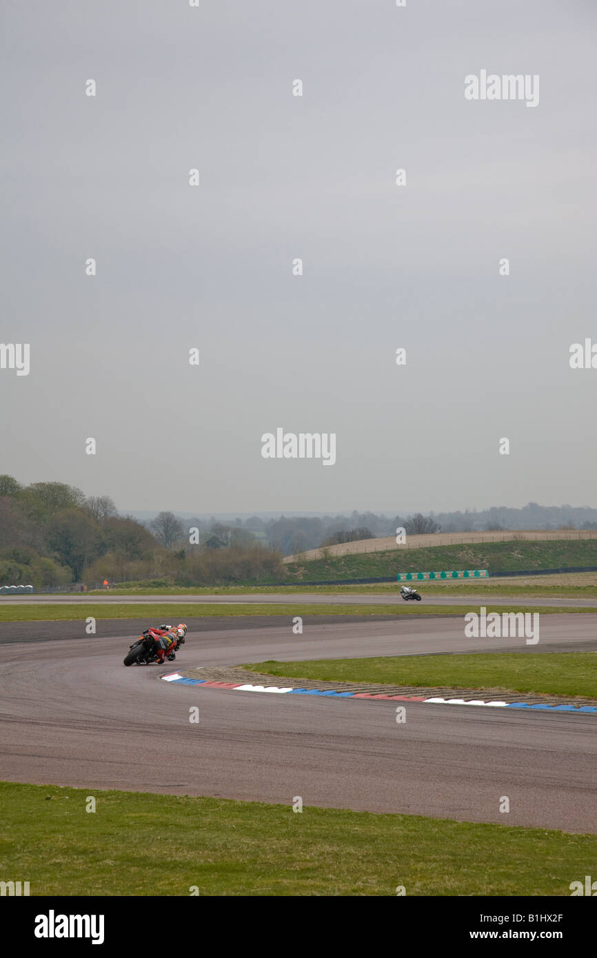 Motociclette da corsa potenza anche se le pieghe a Thruxton, Hampshire, Inghilterra. Foto Stock