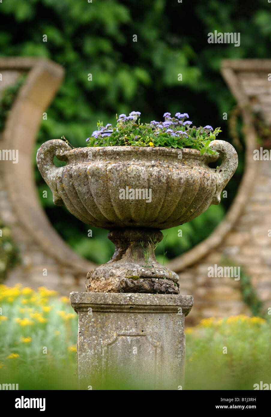 Un antico urna di pietra in un giardino murato con una forma a ferro di cavallo DESIGN FINESTRA REGNO UNITO Foto Stock