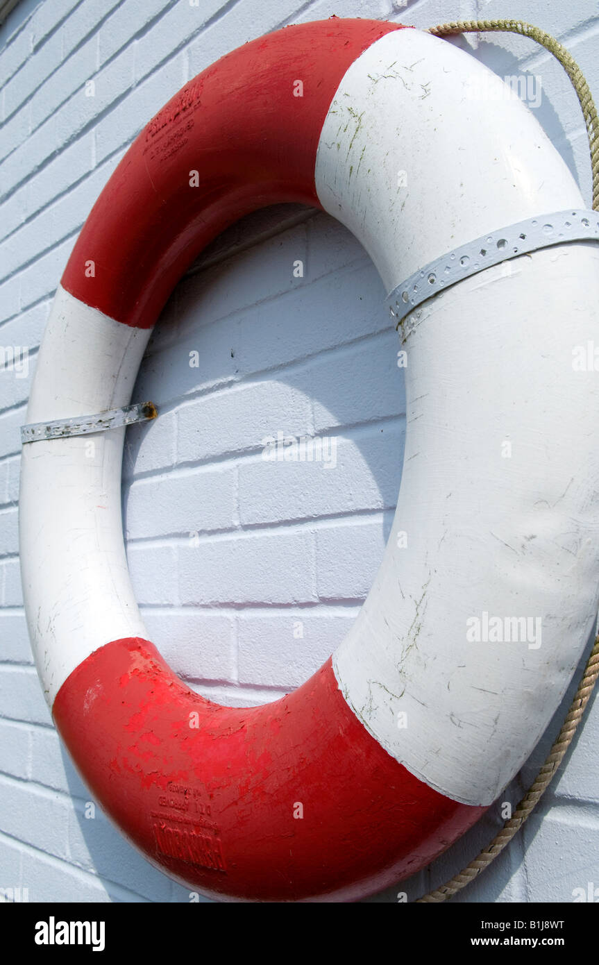 Il bianco e il rosso anello di vita bouy montato su una parete bianca Foto Stock