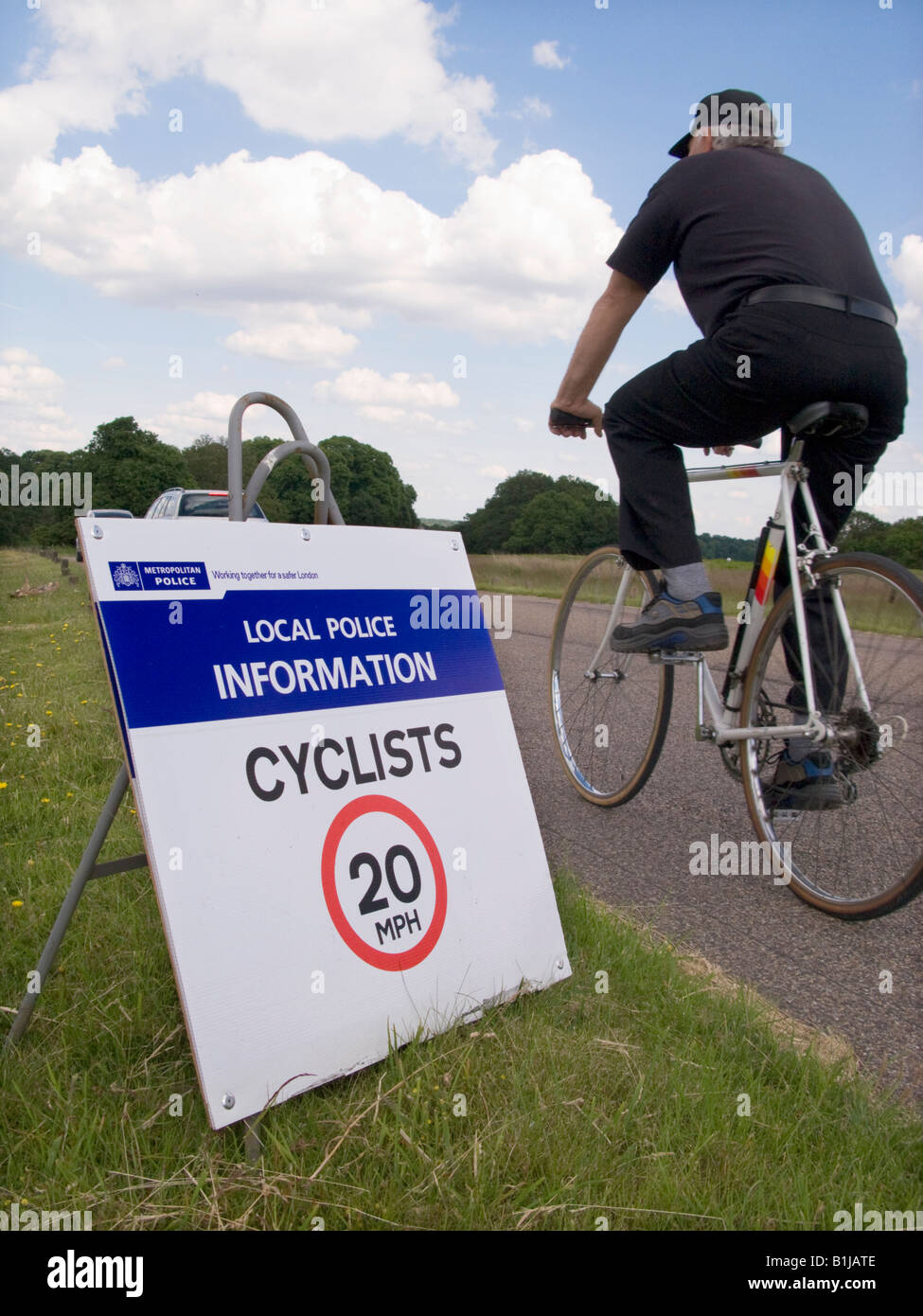 Ciclista e 20 mph segnale di limite di velocità nel Parco di Richmond, Surrey. Regno Unito Foto Stock