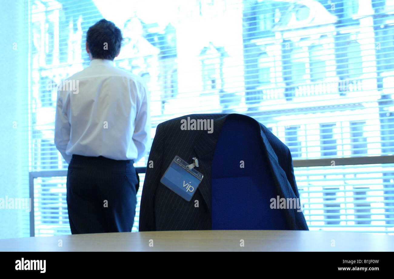 Business man guarda fuori finestra di ufficio con VIP badge in primo piano Foto Stock