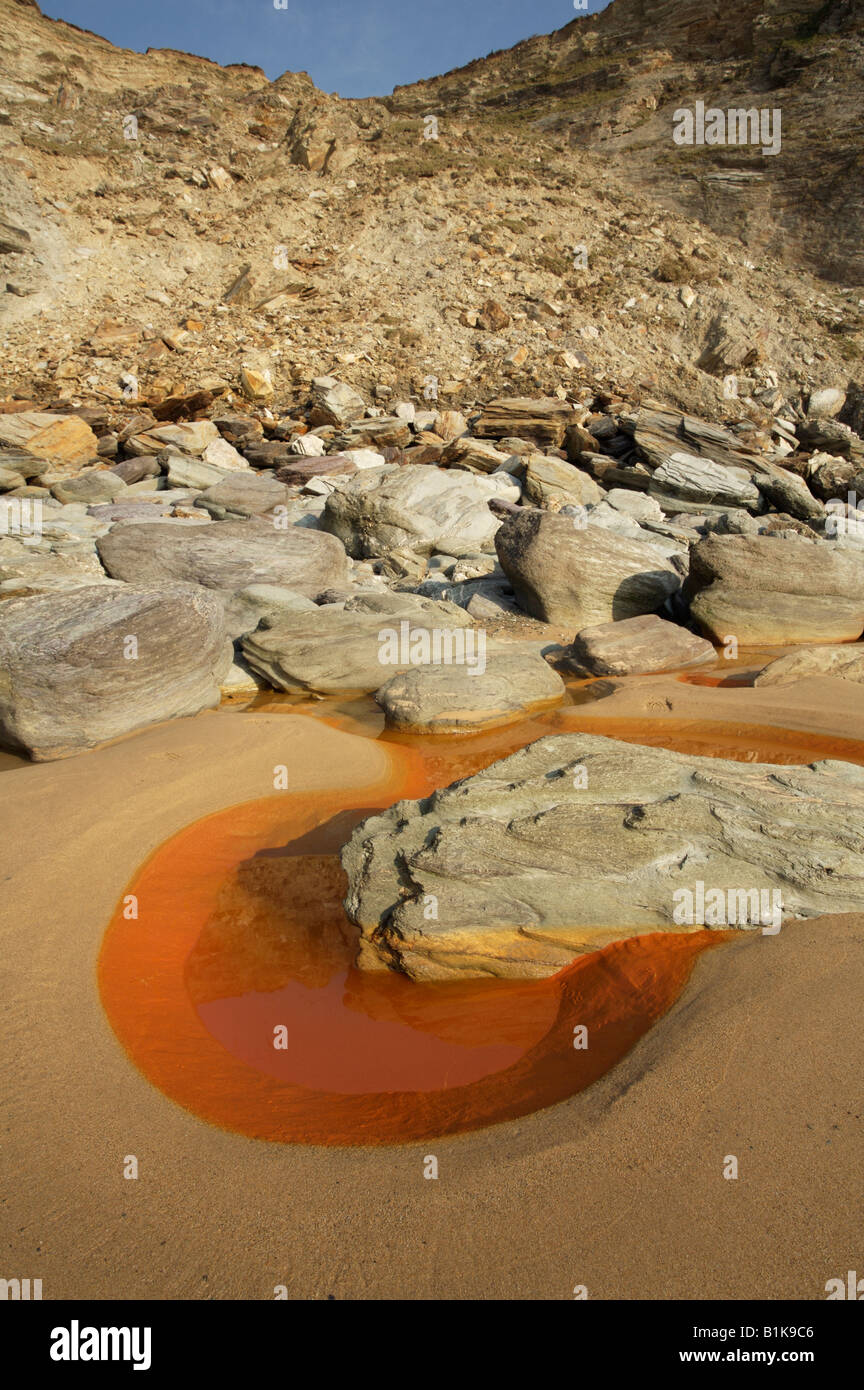 Colore arancio acqua su una spiaggia in North Cornwall, Regno Unito, causati da eventi naturali pigmento color ocra in massa Foto Stock