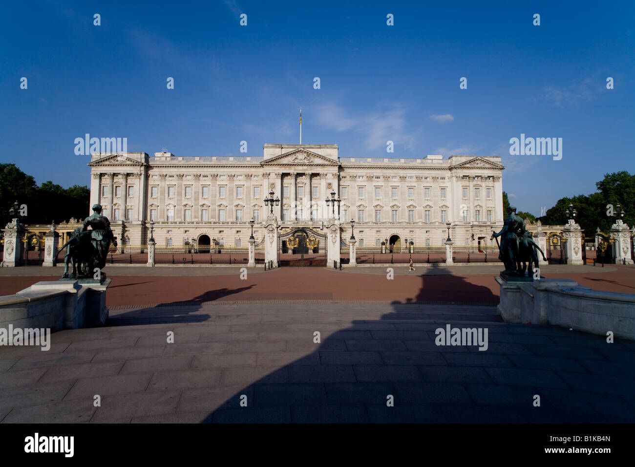 Un " commuter " passeggiate oltre la parte anteriore del Buckingham Palace, visto dal Victoria Memorial su una soleggiata mattina d'estate Foto Stock