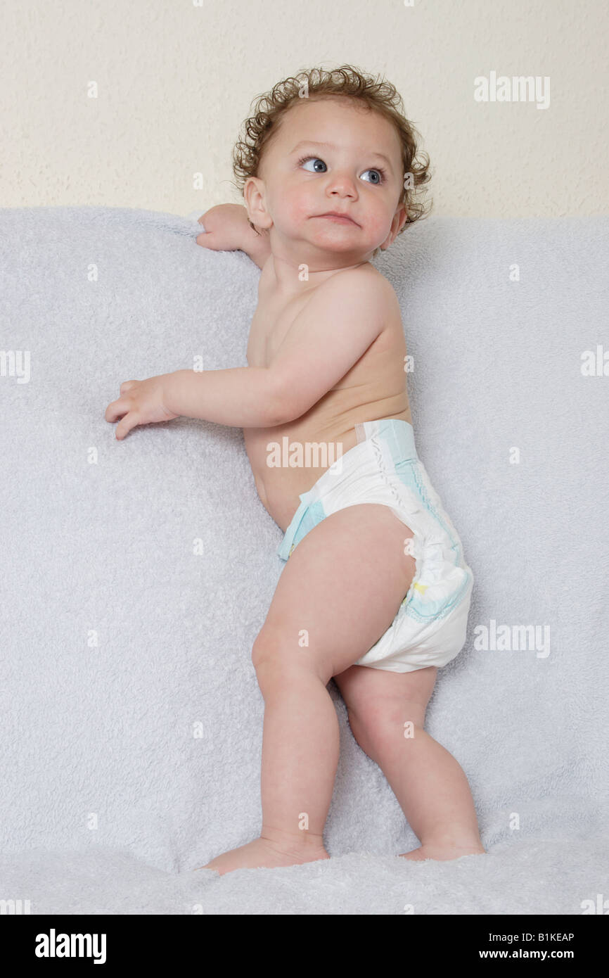 Piccolo bambino in piedi indossando pannolino monouso Foto Stock