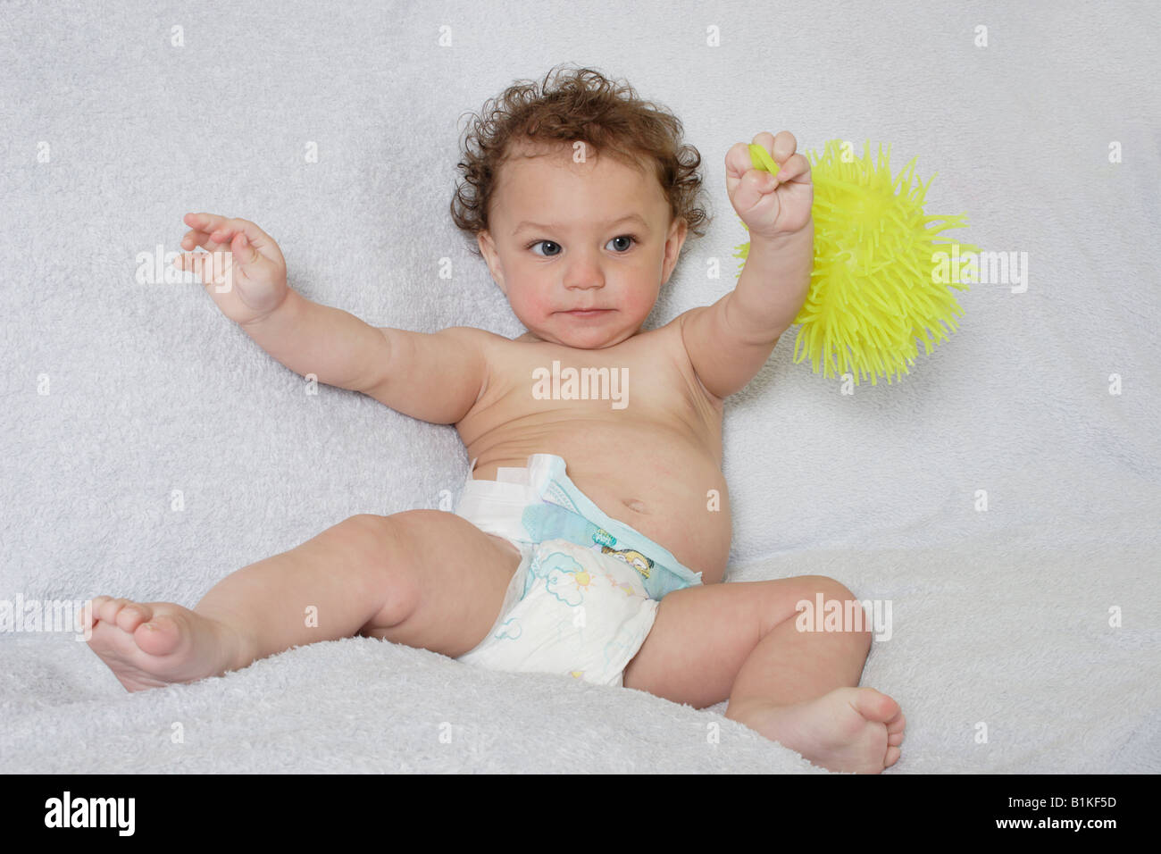 Piccolo bambino nel pannolino monouso azienda giallo giocattolo gommoso Foto Stock