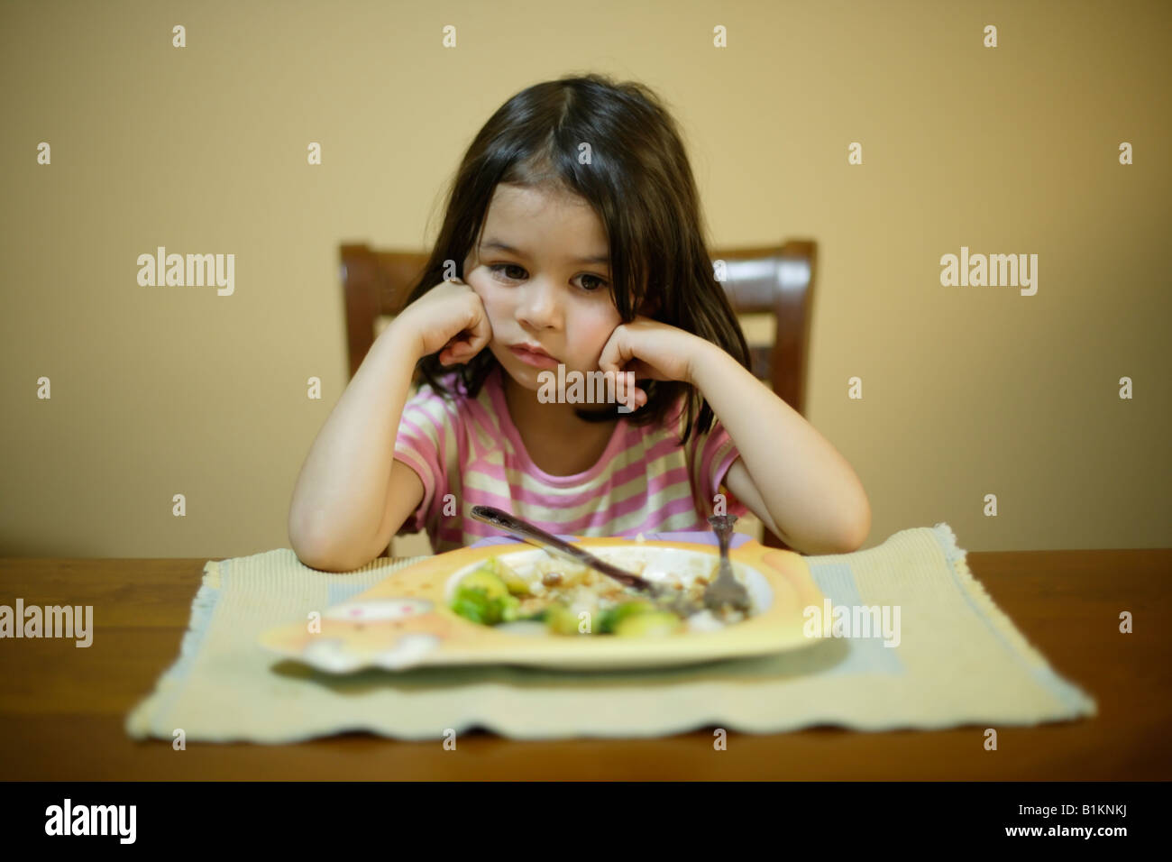Ragazza di età compresa tra i quattro riluttanti a finire le verdure sul suo piatto di arrosto domenicale cena Foto Stock