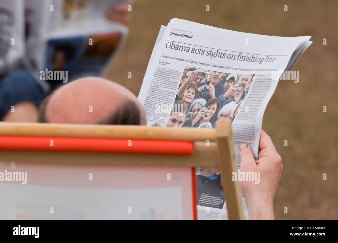 Uomo calvo seduto nella sedia sdraio quotidiano di lettura presso il Guardian Hay Festival 2008 Hay on Wye Powys Wales UK UE Foto Stock