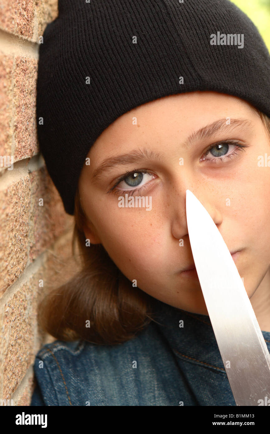 Giovane ragazza adolescente con coltello affilato camicia denim e beany black hat in strada urbana alley con muro di mattoni posti dal modello Foto Stock