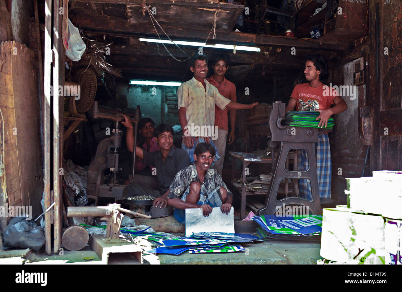 INDIA MUMBAI MAHARASHTRA dei lavoratori in un negozio di fabbricazione di metalli presentano orgogliosamente come hanno tagliato fino lattine metalliche e indicazioni per il riciclaggio Foto Stock