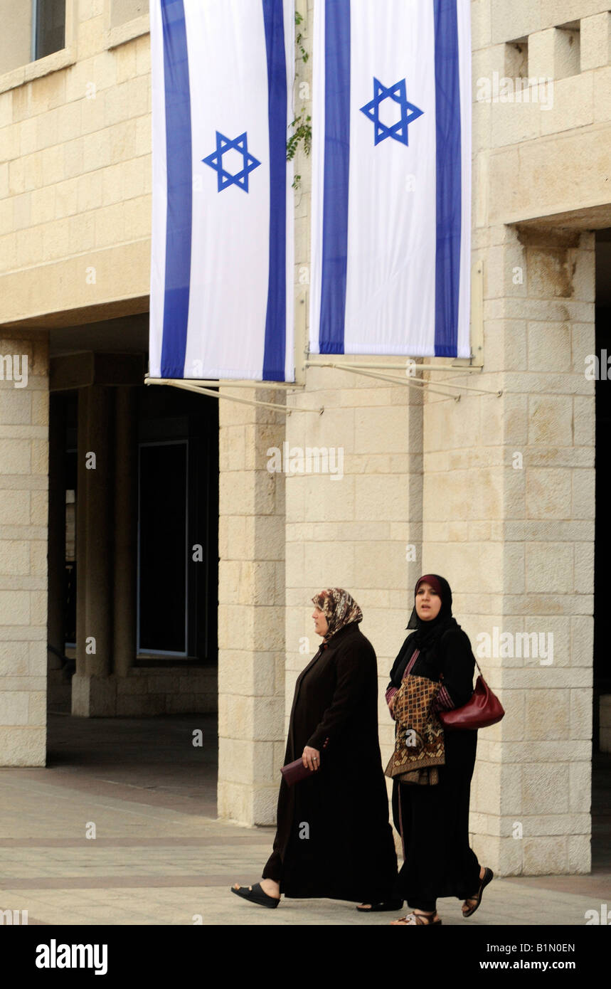 Due donne palestinesi camminare sotto bandiere israeliane nei pressi del palazzo comunale in Gerusalemme. Foto Stock