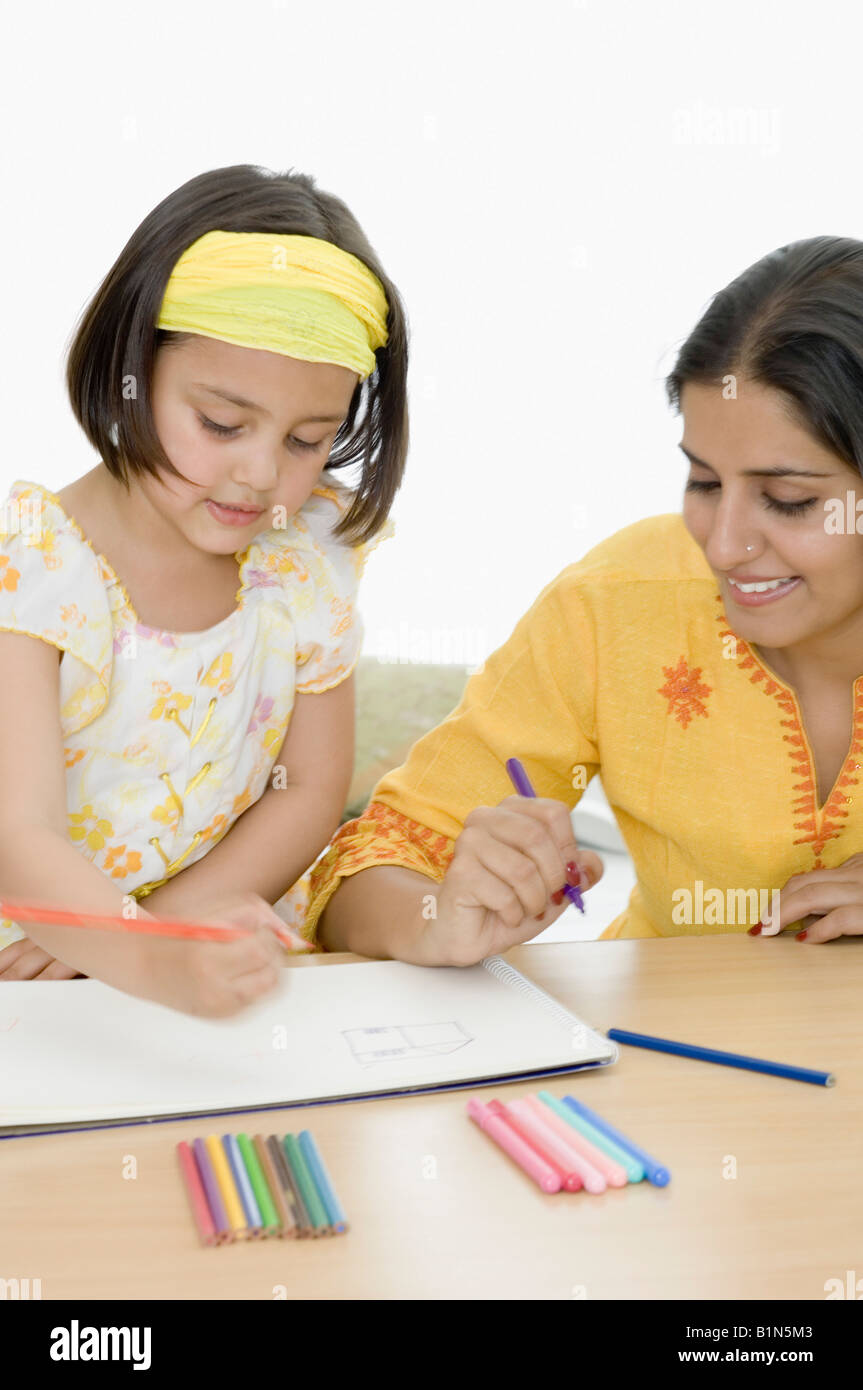 Giovane donna con sua figlia di colorazione su un libro da colorare Foto Stock