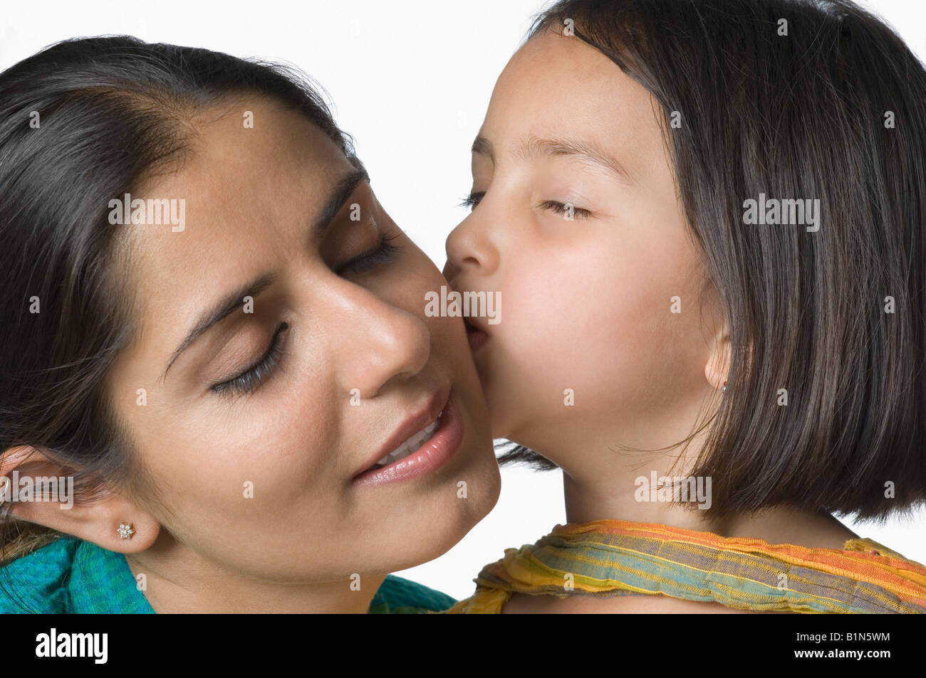 Close-up di una ragazza baciare la madre e sorridente Foto Stock