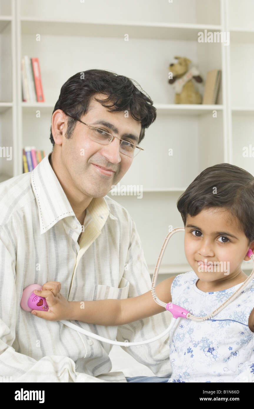Ritratto di una ragazza esaminando il suo padre con uno stetoscopio Foto Stock