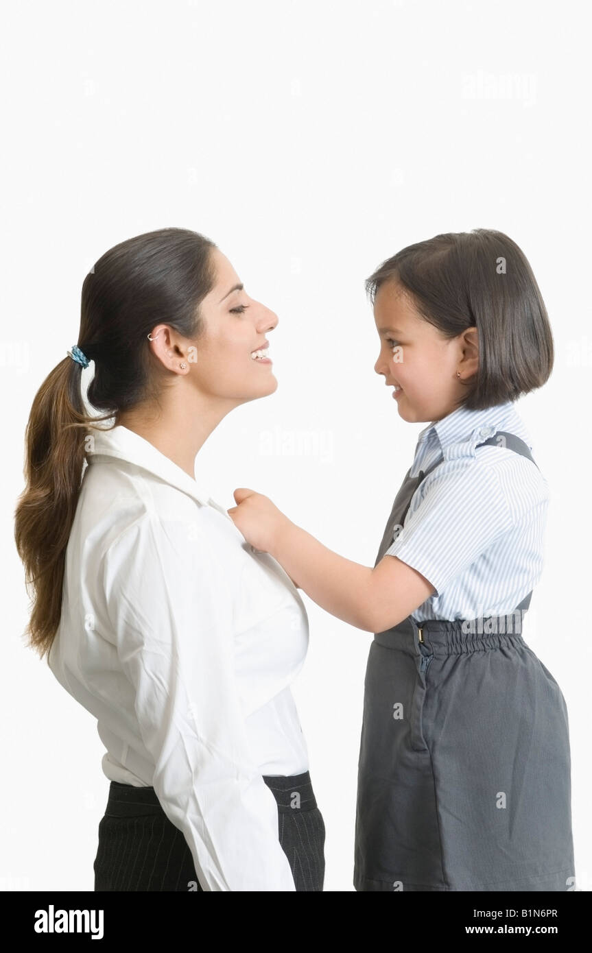Profilo laterale di una ragazza aiutando la madre in abito da indossare e sorridente Foto Stock