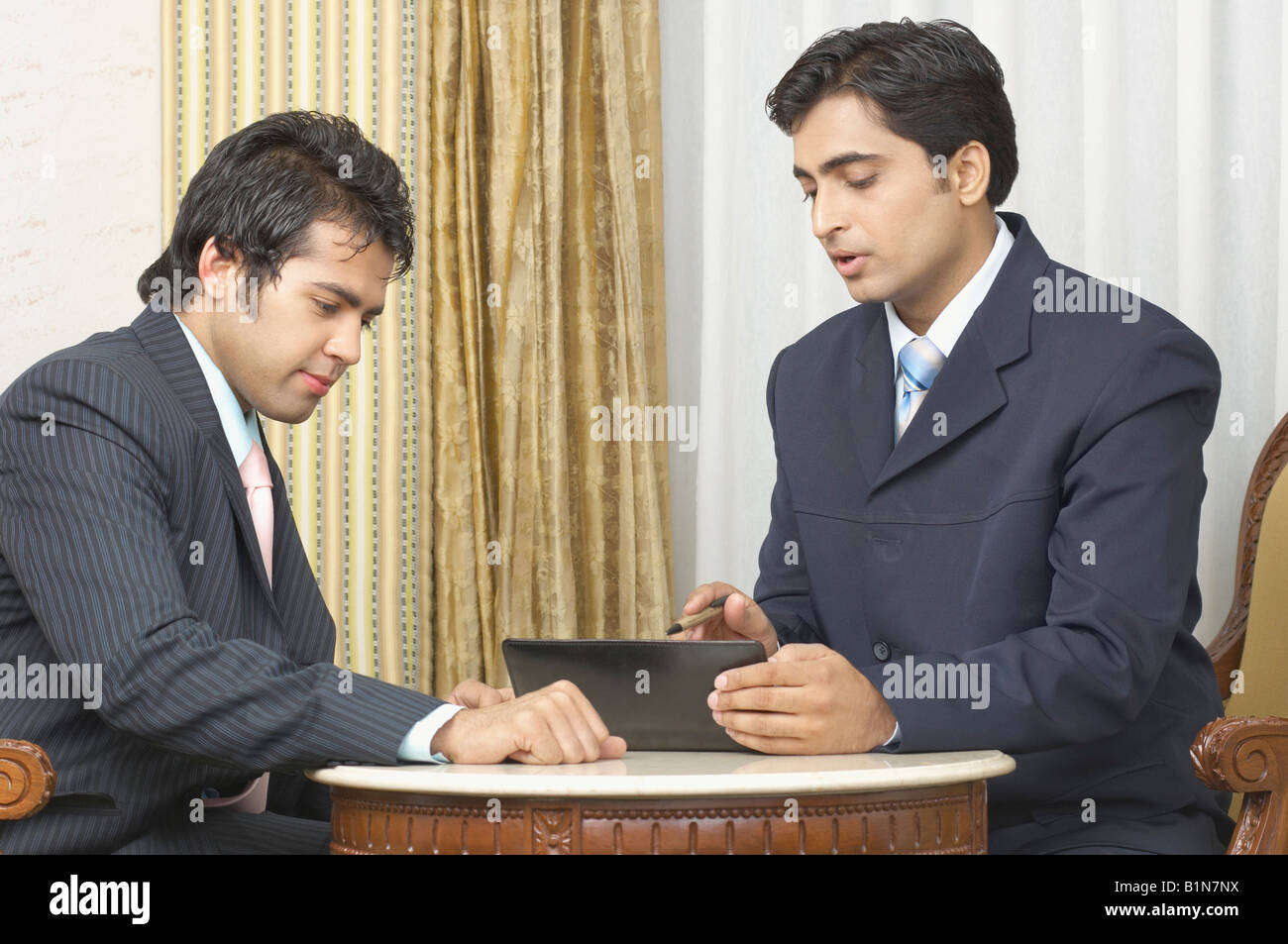Due imprenditori usando un assistente di dati personale e discutere in una camera di hotel Foto Stock