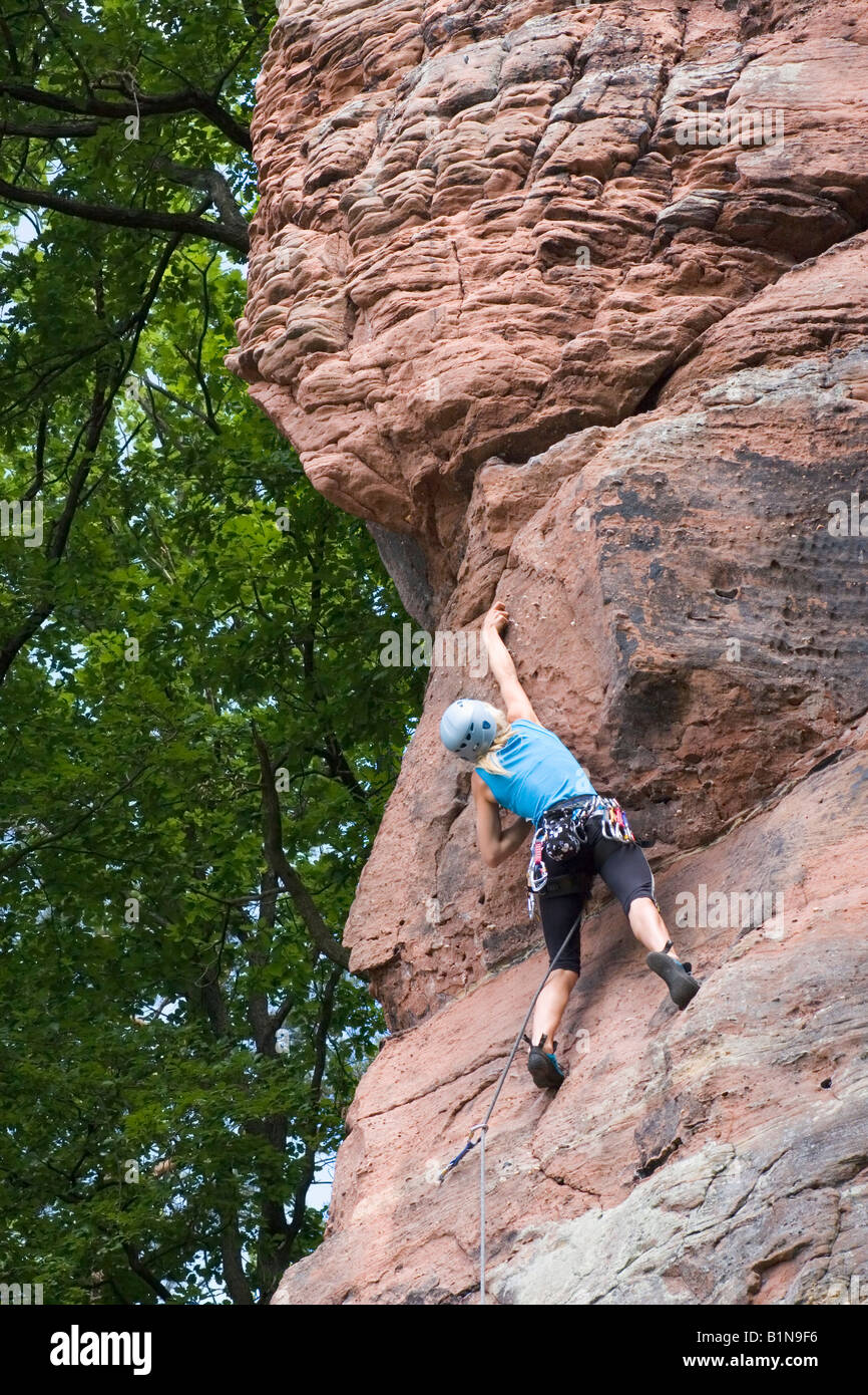 Giovane donna arrampicata roccia arenaria con corda e casco Foto Stock