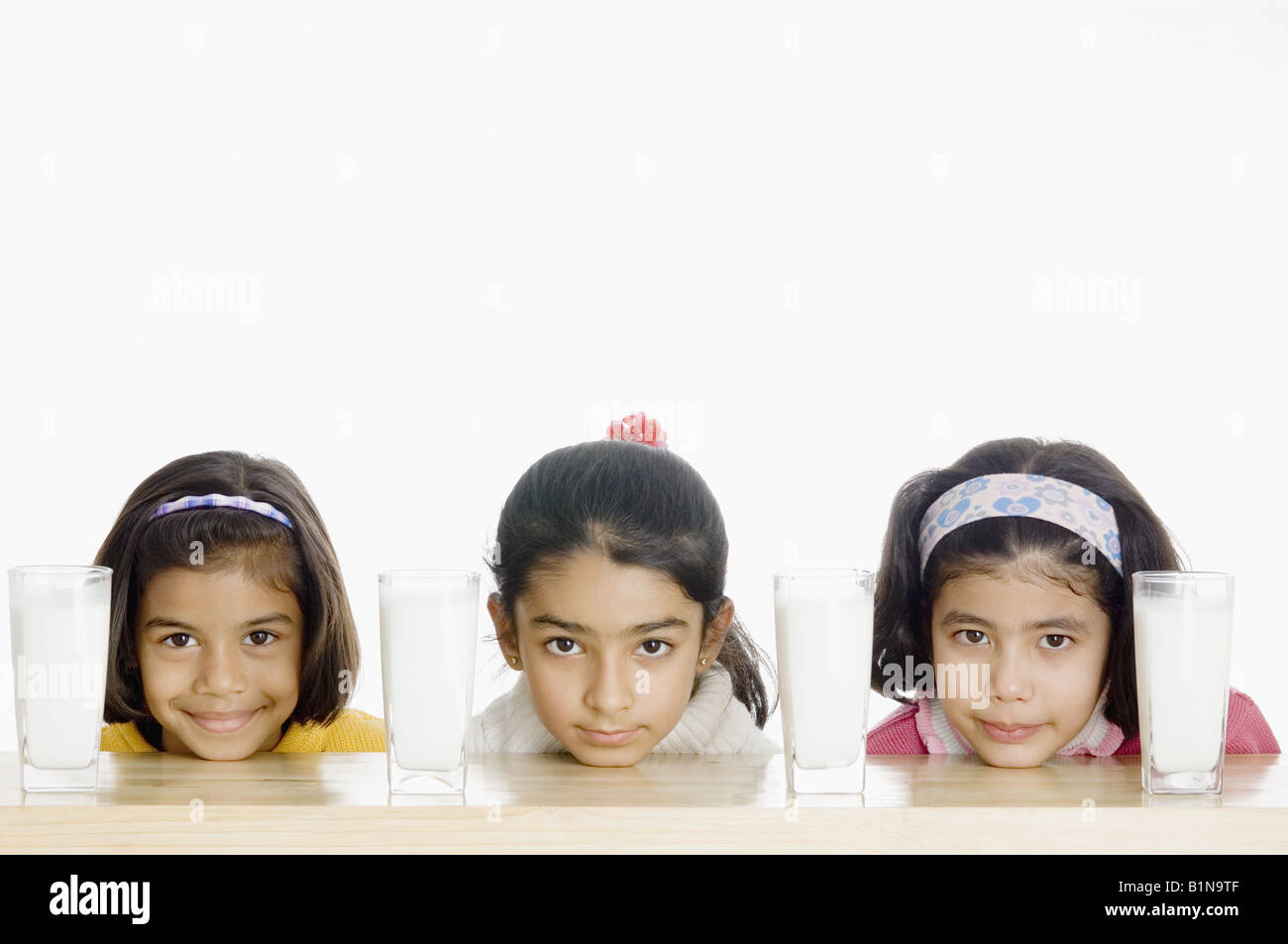 Ritratto di tre ragazze con bicchieri di latte su un tavolo Foto Stock