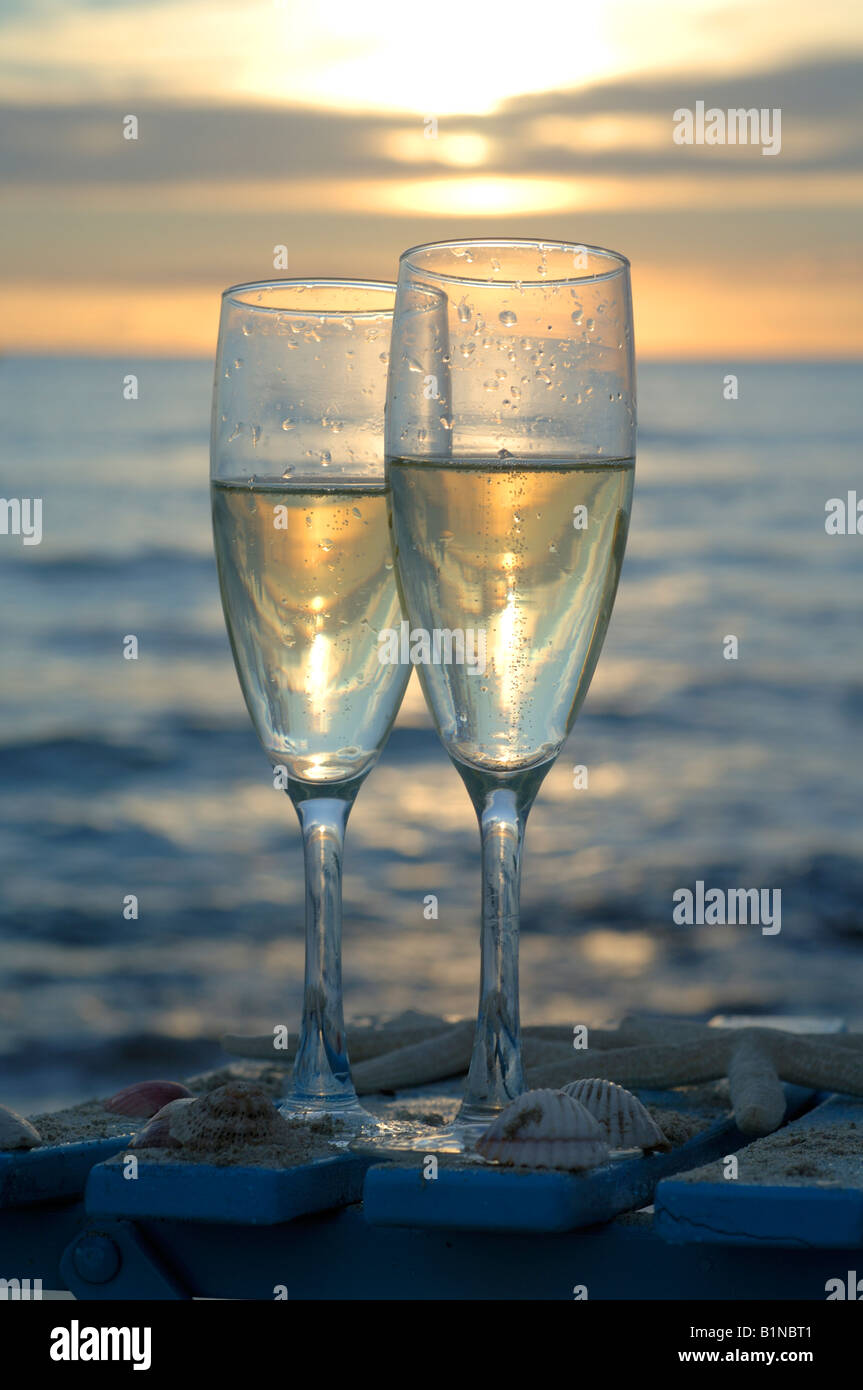 Due bicchieri di vino spumante su una sedia in spiaggia al tramonto Foto  stock - Alamy