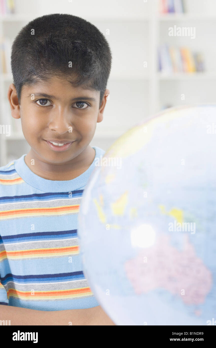 Ritratto di un ragazzo sorridente dietro un globo Foto Stock