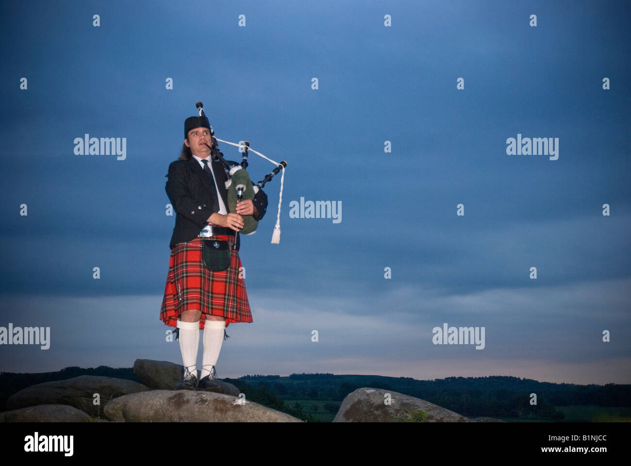 Un lone bagpiper stagliano a tarda sera sky Foto Stock