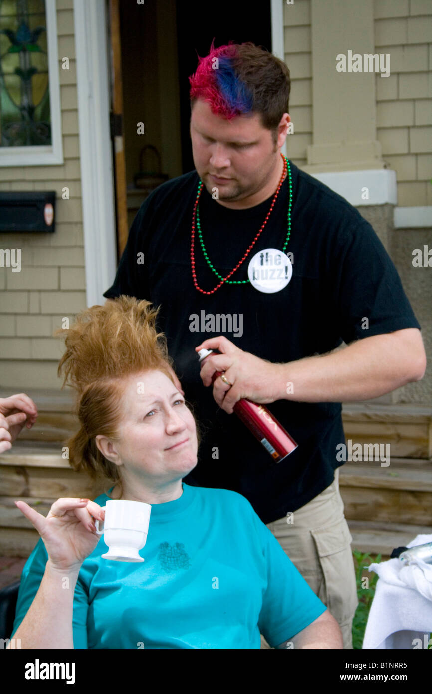 Donna godendo di tazza di birra mentre estetista crea il suo stile buzz in outdoor di bellezza. Grand Old giorno St Paul Minnesota USA Foto Stock