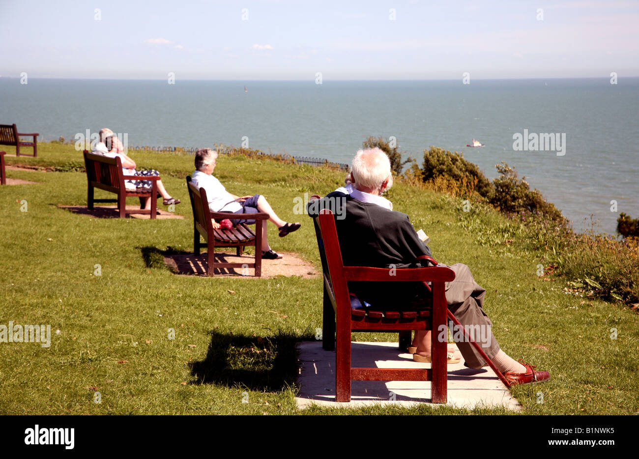 Gli anziani seduti sulle panchine sul fronte mare, Inghilterra Foto Stock