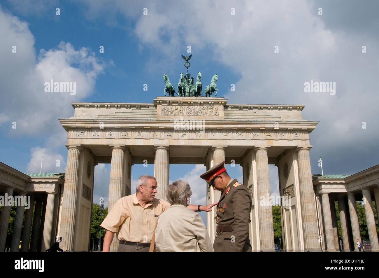 I turisti con un busker vestito come ex soldato DDR al Brandenburger Tor, Branderburg gate in Pariser Platz Berlino Germania Foto Stock