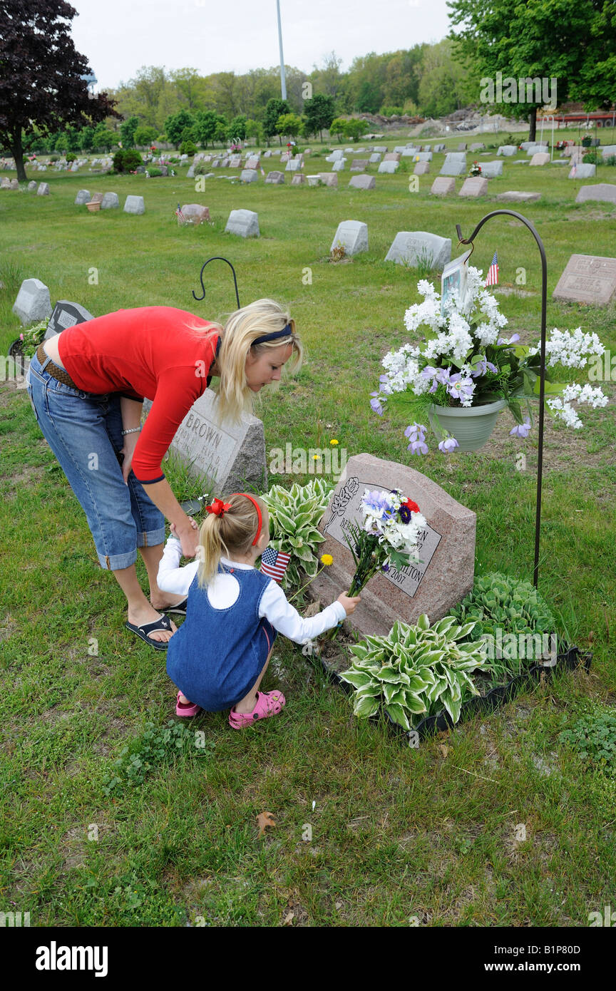 Madre e figlia luoghi fiori sul luogo di sepoltura Foto Stock