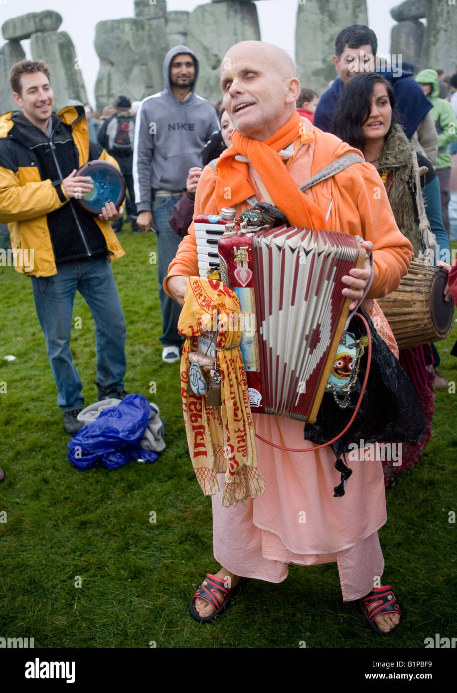 Hare Krisna suonando la fisarmonica presso il Solstizio d'estate Stonehenge WILTSHIRE REGNO UNITO Europa Foto Stock