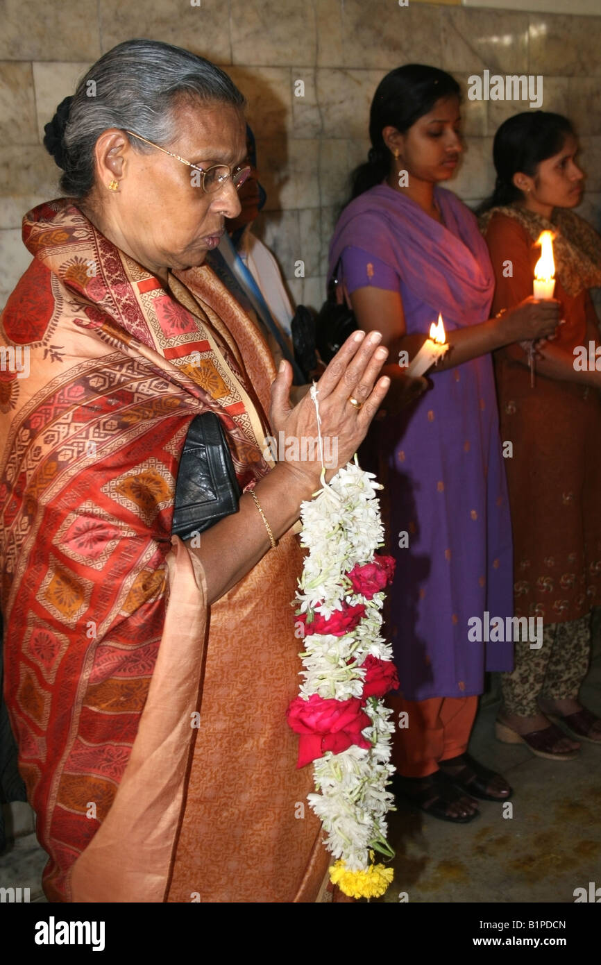 Cattolica le donne indiane Tenere candele e ghirlande di fiori e il culto a Gesù Bambino la Chiesa Cattolica , Bangalore , India Foto Stock