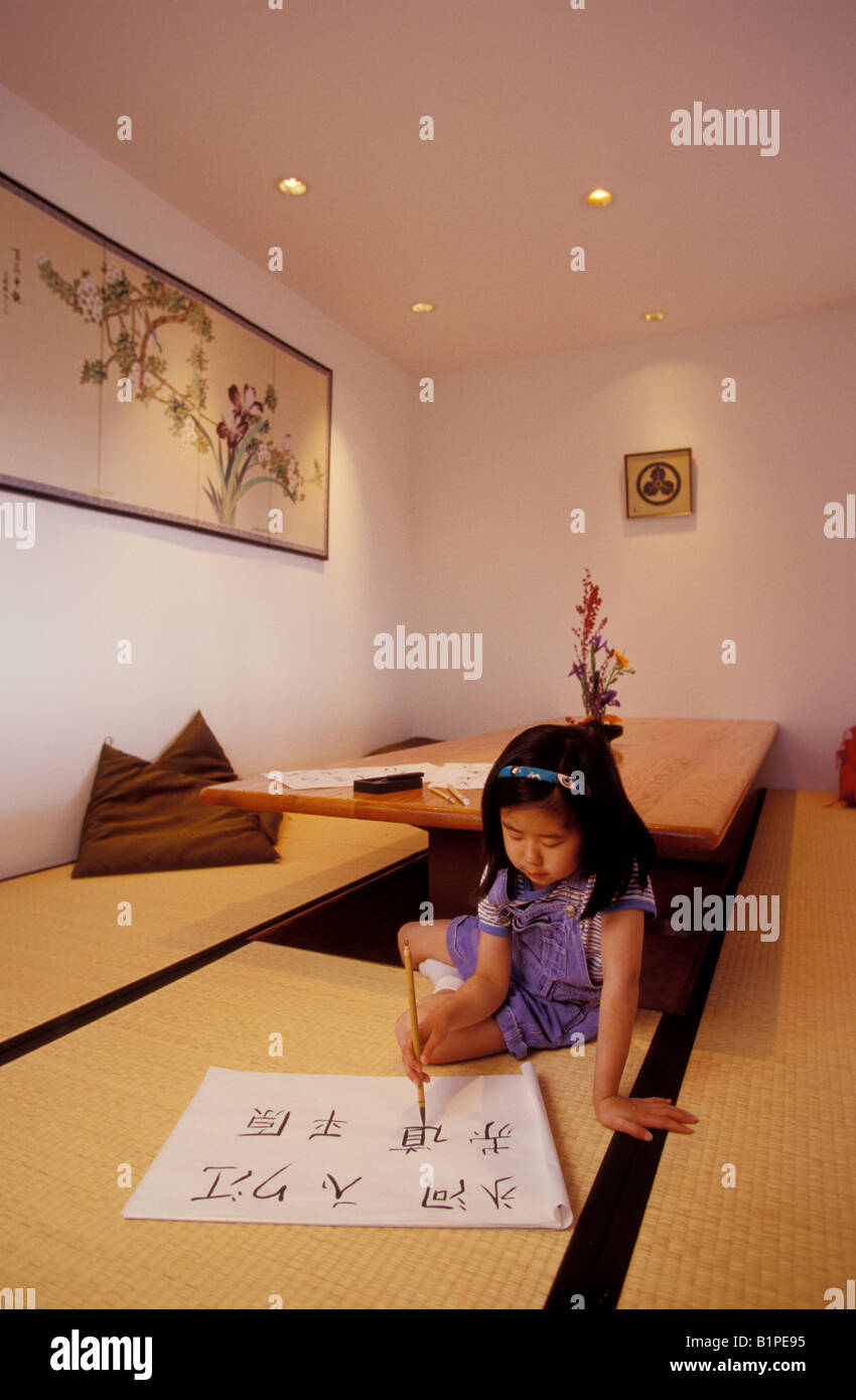 Una bambina di cinque anni le pratiche di calligrafia giapponese in stile Giapponese sala da pranzo di casa sua in Bellevue Washington Foto Stock
